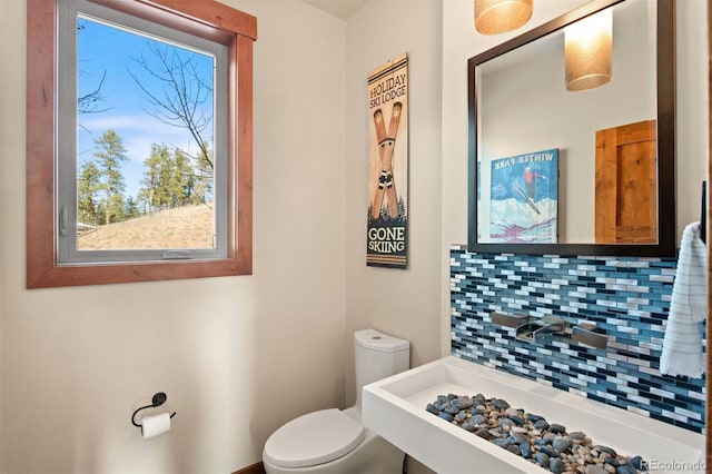 bathroom featuring tasteful backsplash, toilet, and sink