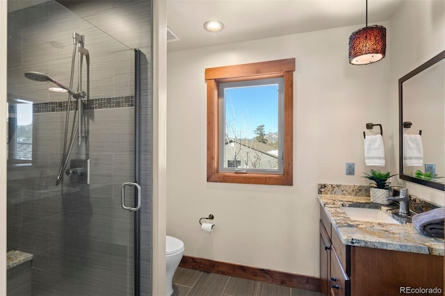 bathroom with vanity, toilet, and a shower with door