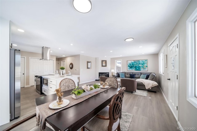 dining area with a brick fireplace and light hardwood / wood-style floors