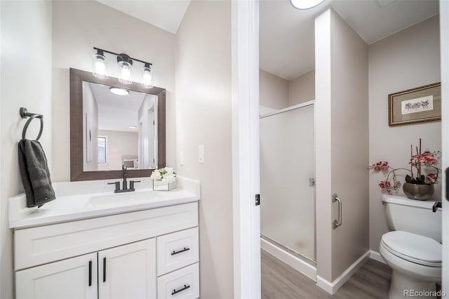 bathroom with vanity, toilet, a shower with door, and wood-type flooring