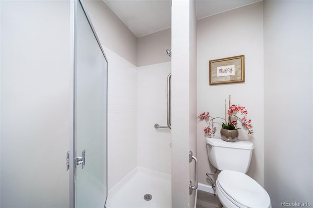 bathroom with hardwood / wood-style flooring, a shower, and toilet