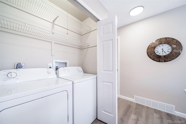 laundry room with washer and dryer and light hardwood / wood-style flooring