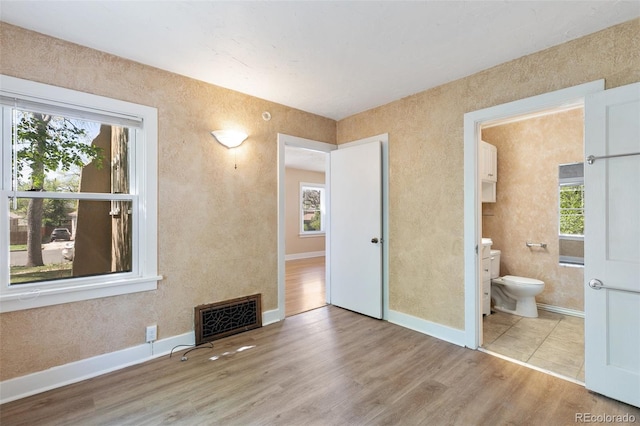 924 E Saint Vrain St, Colorado Springs, CO 80903 - unfurnished bedroom with wood finished floors, multiple windows, connected bathroom, and baseboards