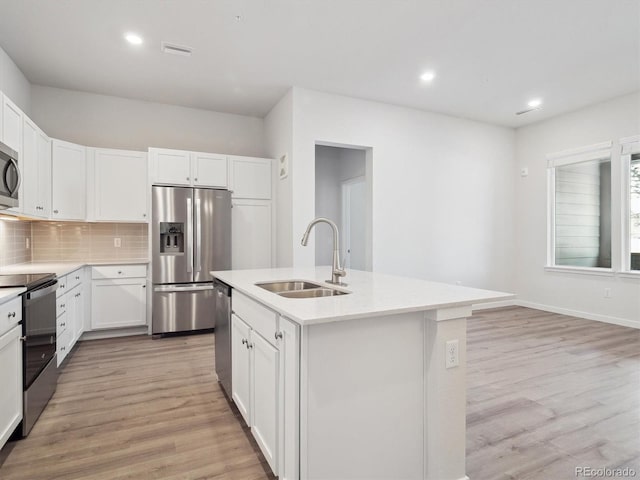 kitchen with stainless steel appliances, tasteful backsplash, light countertops, light wood-style flooring, and a sink