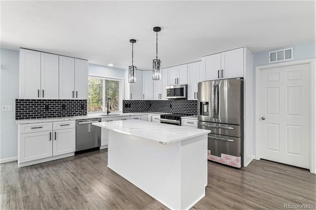 1963 Hogan Ct, Castle Rock, CO 80109 - kitchen with stainless steel appliances, a sink, wood finished floors, white cabinetry, and decorative backsplash