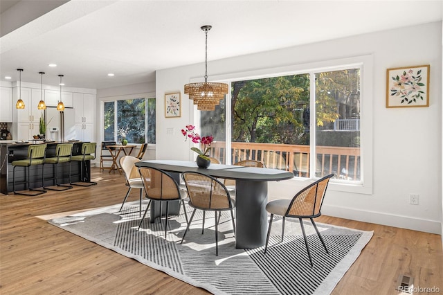 dining space with light wood-type flooring and an inviting chandelier