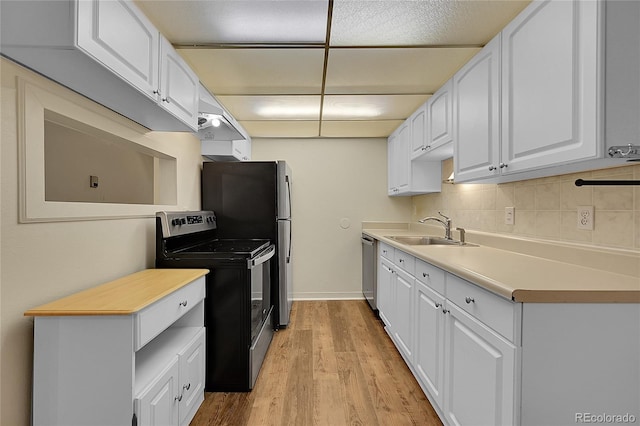 kitchen with sink, white cabinetry, tasteful backsplash, light hardwood / wood-style flooring, and appliances with stainless steel finishes