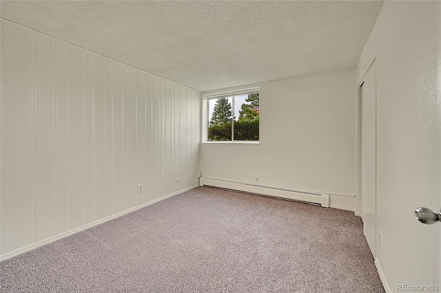 spare room featuring a baseboard radiator, carpet flooring, and a textured ceiling