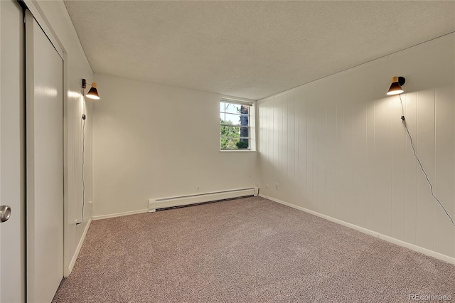 basement with carpet, a baseboard heating unit, and a textured ceiling