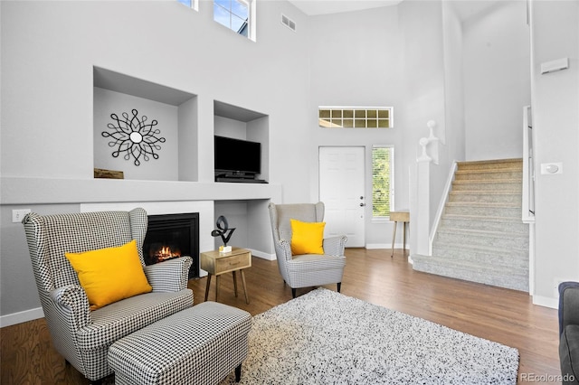 1464 Spotted Owl Way, Highlands Ranch, CO 80129 - living area featuring stairs, wood finished floors, a glass covered fireplace, and a towering ceiling