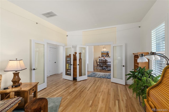 corridor featuring light wood-style floors, french doors, visible vents, and baseboards