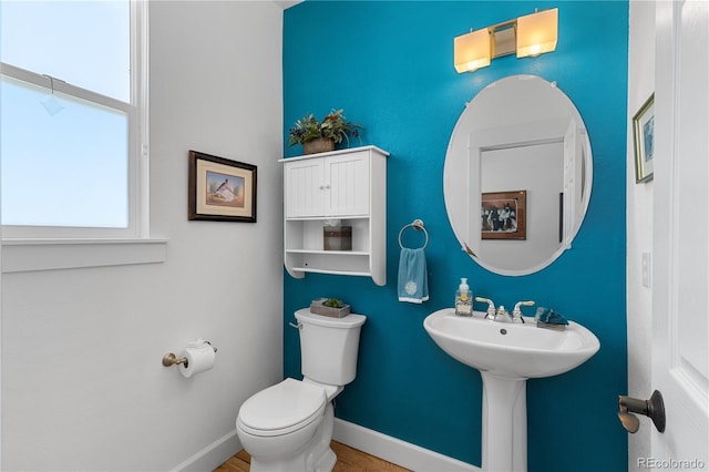 half bath with a sink, toilet, and baseboards