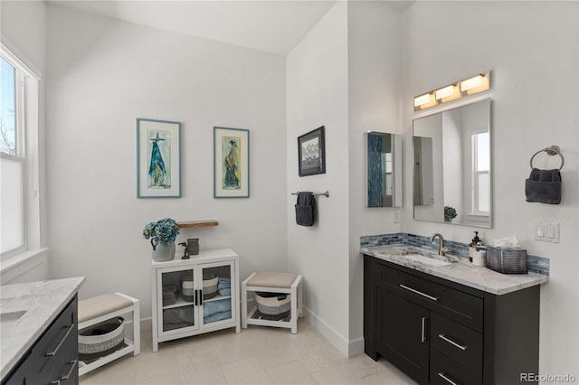 full bathroom featuring a healthy amount of sunlight, vanity, and baseboards