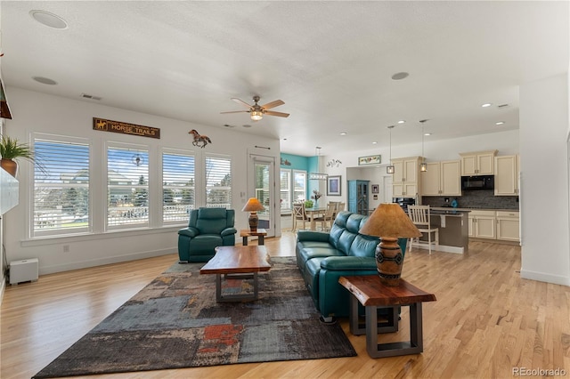 living room featuring visible vents, ceiling fan, light wood-style flooring, and baseboards