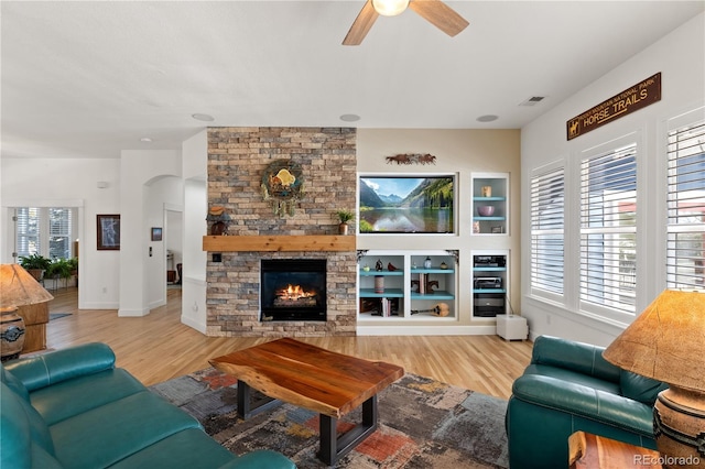 living area featuring arched walkways, visible vents, a fireplace, and wood finished floors