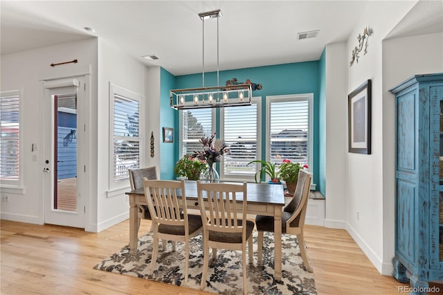 dining space featuring light wood-style floors, baseboards, visible vents, and an inviting chandelier