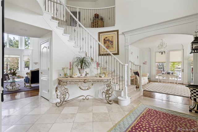 tiled entryway with stairway, a high ceiling, arched walkways, and a wealth of natural light