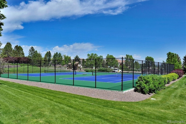 view of tennis court with a yard and fence