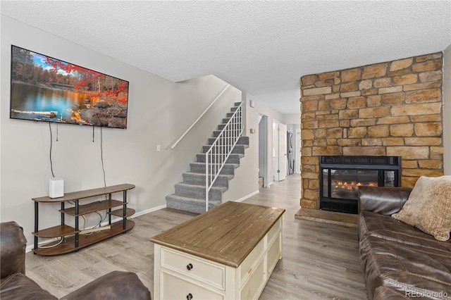 living room with a fireplace, a textured ceiling, and light wood-type flooring