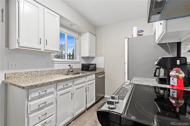 kitchen featuring light stone countertops, appliances with stainless steel finishes, sink, light hardwood / wood-style flooring, and white cabinets