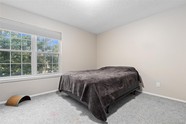 bedroom with light colored carpet and a textured ceiling