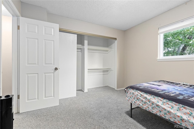 bedroom featuring light colored carpet, a textured ceiling, and a closet