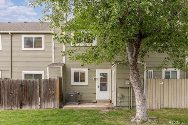 rear view of property with central AC and a lawn