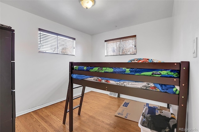 bedroom with hardwood / wood-style floors and refrigerator