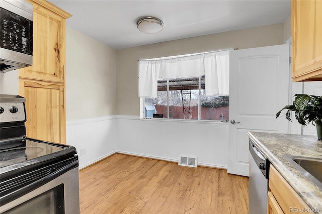 kitchen with sink, light brown cabinetry, light wood-type flooring, and appliances with stainless steel finishes