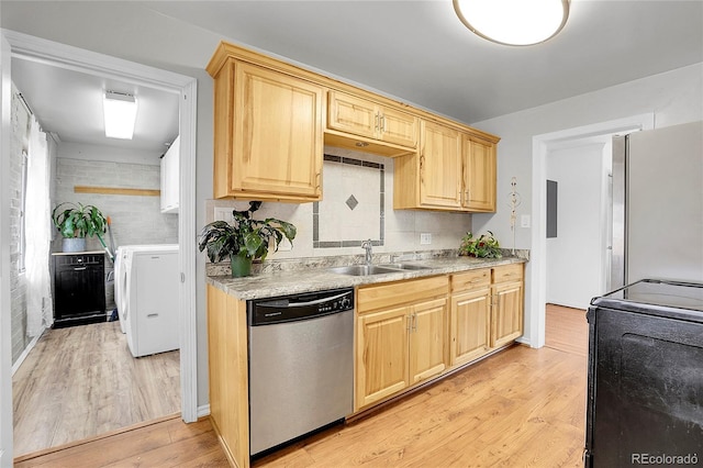 kitchen with washing machine and dryer, sink, stainless steel appliances, and light wood-type flooring