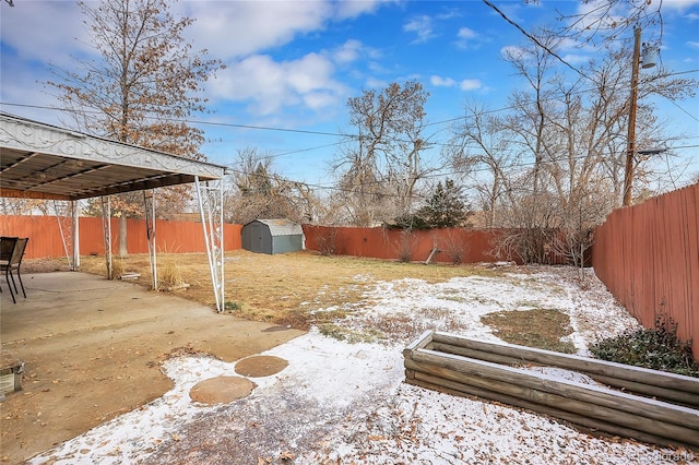 yard covered in snow with a storage unit and a patio area