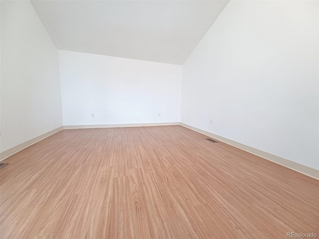 empty room featuring light hardwood / wood-style flooring and vaulted ceiling