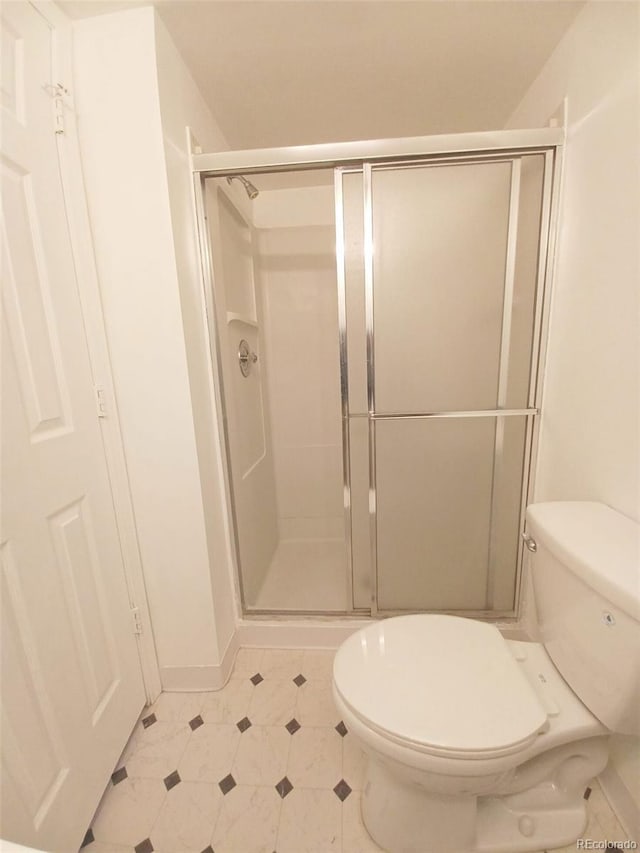 bathroom featuring a shower with door and toilet