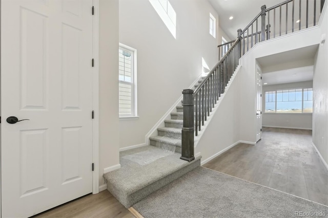 staircase with a towering ceiling and hardwood / wood-style floors