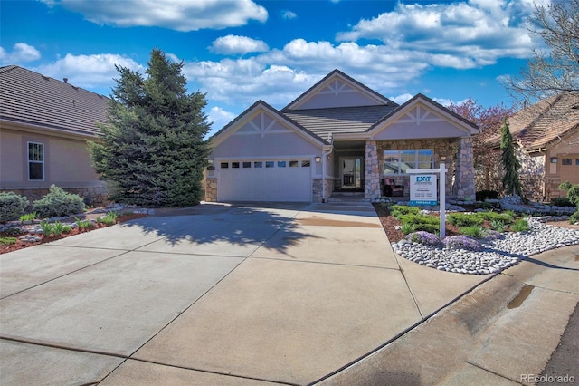 view of front facade with a tiled roof, a garage, stucco siding, concrete driveway, and stone siding