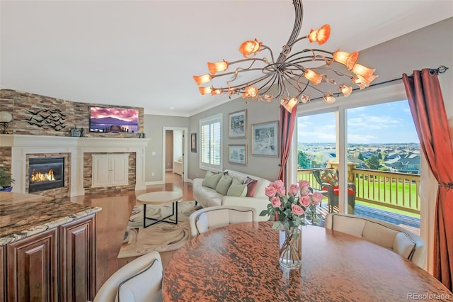 dining room featuring wood finished floors, a fireplace, baseboards, and a notable chandelier