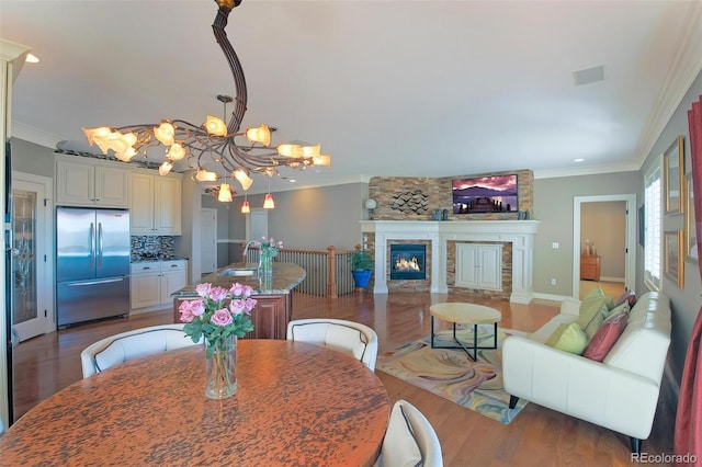 dining area with ornamental molding, light wood-style floors, a chandelier, a fireplace, and recessed lighting