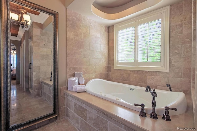 bathroom featuring a shower stall, tile walls, an inviting chandelier, and a whirlpool tub