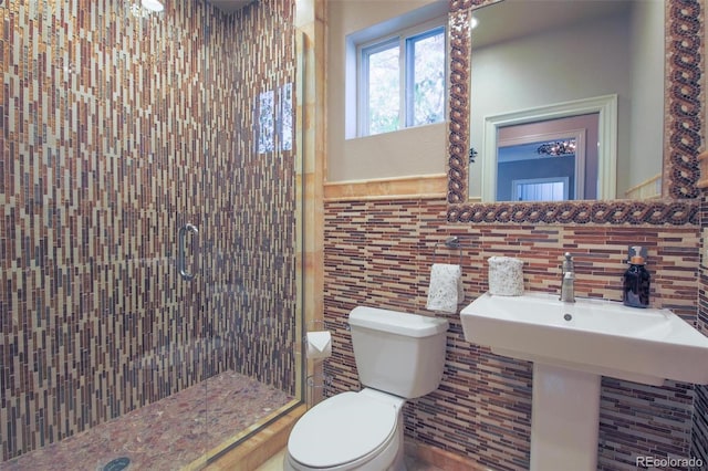 full bathroom with a stall shower, toilet, a sink, and tile walls