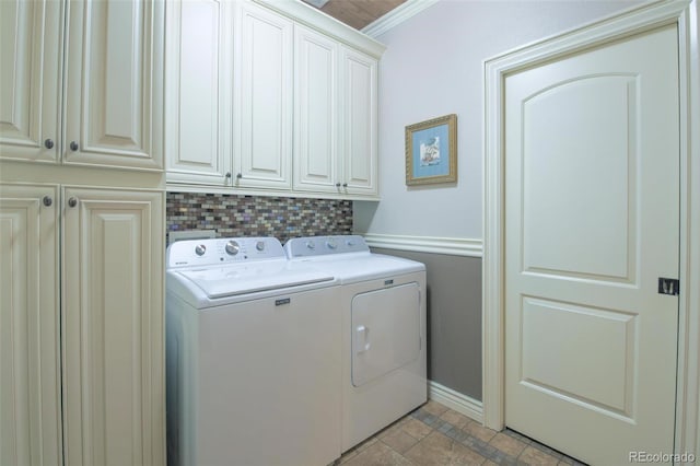 laundry area featuring cabinet space, ornamental molding, stone finish floor, washing machine and clothes dryer, and baseboards