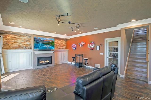 living area with wood finished floors, visible vents, recessed lighting, crown molding, and a glass covered fireplace