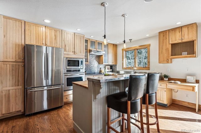 kitchen featuring stainless steel appliances, a breakfast bar area, a center island, and dark wood-type flooring