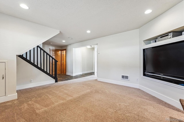 unfurnished living room with carpet floors and a textured ceiling