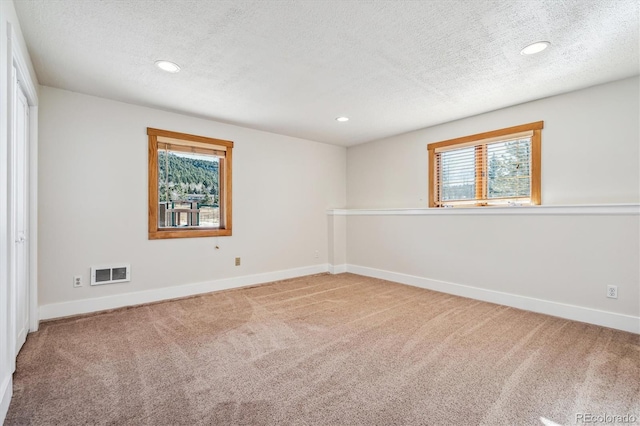 carpeted empty room with a textured ceiling