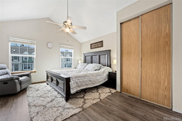 bedroom with a closet, baseboards, wood finished floors, lofted ceiling, and ceiling fan