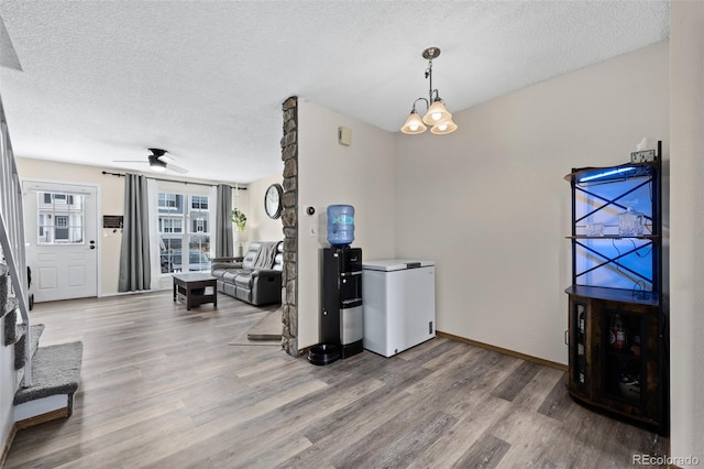 interior space featuring baseboards, a textured ceiling, a ceiling fan, and wood finished floors