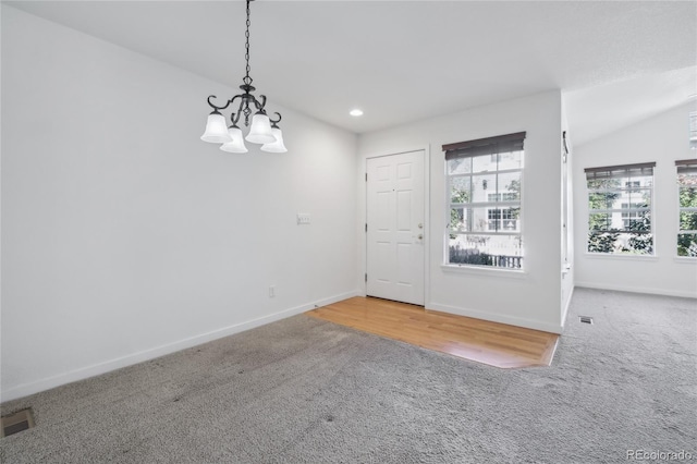 carpeted foyer entrance featuring lofted ceiling and a chandelier