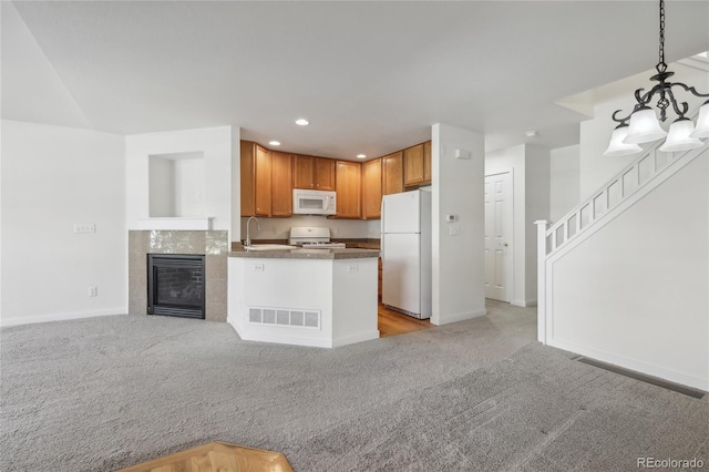 kitchen featuring kitchen peninsula, sink, pendant lighting, light colored carpet, and white appliances