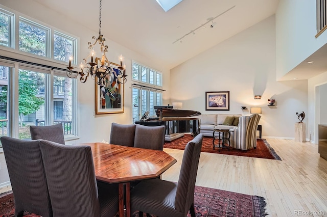 8505 E Temple Dr Unit 473, Denver, CO 80237 - dining area with rail lighting, high vaulted ceiling, a chandelier, and hardwood / wood-style flooring
