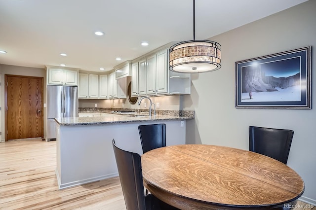 8505 E Temple Dr Unit 473, Denver, CO 80237 - kitchen with freestanding refrigerator, light stone counters, a peninsula, light wood-type flooring, and recessed lighting